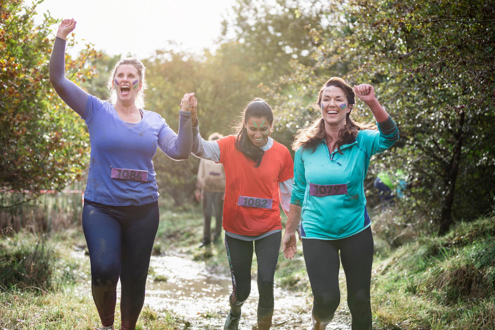 Cheerful women finishing muddy charity run together